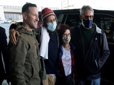 Le journaliste américain Danny Fenster (avec un bonnet) a retrouvé sa famille mardi 16 novembre à l'aéroport JFK de New York après sa libération d'une prison birmane grâce aux bons offices de l'ancien diplomate américain Bill Richardson. - TIMOTHY A. CLARY [AFP]