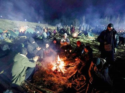 Des migrants espérant pouvoir entrer en Pologne se réchauffent autour d'un feu dans la région de Grodno (Bélarus), le 16 novembre 2021 - Maxim GUCHEK [BELTA/AFP]
