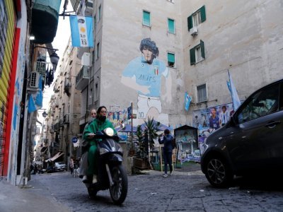 Un scooter passe devant une fresque représentant la légende du football argentin Diego Maradona dans les "quartiers espagnols" de Naples, le 23 novembre 2021 - Carlo Hermann [AFP]
