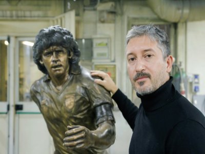 Le sculpteur italien Domenico Sepe pose avec son oeuvre en bronze représentant Diego Maradona dans son atelier à Naples, le 22 novembre 2021 - Carlo Hermann [AFP]