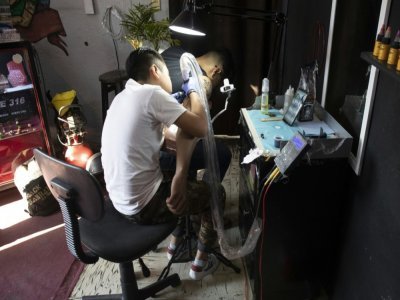 Brandon Burgos, 11 ans, réalise un tatouage sur un client, le 10 novembre 2021 à Puebla, au Mexique - JUAN CARLOS SANCHEZ [AFP]
