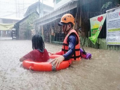 Un agent des garde-côtes aide une habitante de Cagayan de Oro, dans l'île philippine de Mindanao, à évacuer son domicile pendant des inondations apportées par le super-typhon Rai, le 16 décembre 2021 - Handout [AFP]