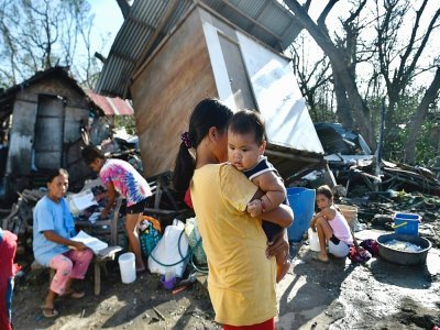 Habitants près d'une maison détruite par le typhon Rai, à Carcar, dans la province de Cebu aux Philippines, le 18 décembre 2021 - VICTOR KINTANAR [AFP]