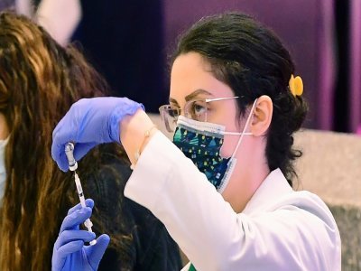 Une pharmacienne prépare une dose de vaccin contre le Covid-19 dans un centre de vaccination à l'aéroport de Los Angeles, le 22 décembre 2021 - Frederic J. BROWN [AFP]