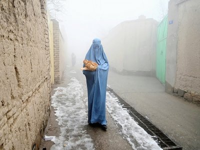 Femme en burqa dans une rue de Kaboul après avoir reçu un pain distribué dans le cadre de la campagne Save Afghans From Hunger le 18 janvier 2022 - Wakil KOHSAR [AFP]