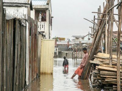 Des habitants marchent dans l'eau qui a inondé le quartier d'Antohomadinika, à Antananarivo, le 24 janvier 2022, après le passage de la tempête tropicale Ana - RIJASOLO [AFP]
