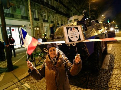 Une manifestante soutenant les convois anti-pass vaccinal devant un blindé de la gendarmerie, le 11 février 2022 place Denfert-Rochereau à Paris - Sameer Al-DOUMY [AFP]