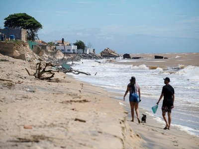 Des promeneurs sur la plage d'Atafona, cité balnéaire qui disparaît peu à peu sous l'océan, le 7 février 2022 au Brésil - MAURO PIMENTEL [AFP]