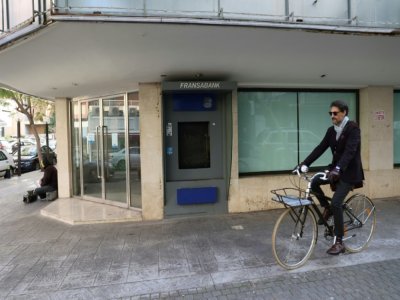 Un cycliste passant devant une succursale bancaire fermée dans la capitale libanaise, Beyrouth, le 18 février 2022 - ANWAR AMRO [AFP]