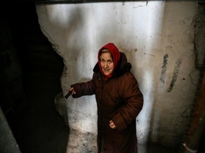Une femme âgée descend dans la cave de son immeuble à la lueur d'une lampe torche pour se protéger des bombardements à Chtchastian près de Lougansk, en Ukraine, le 22 février 2022 - Aris Messinis [AFP]