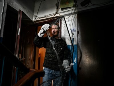 Un homme déblaie des vitres cassées dans sa maison à Chtchastia, près de Lougansk, en Ukraine, le 22 février 2022, après les bombardements russes de la nuit - Aris Messinis [AFP]