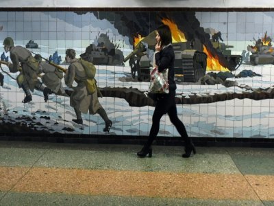 Une femme passe devant une mosaïque murale représentant une scène de bataille de la Deuxième guerre mondiale dans la ville russe de Rostov-sur-le-Don frontalière de l'Ukraine le 22 février 2022. - Olga MALTSEVA [AFP]