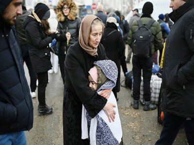 Une femme réconforte un enfant en attendant un mode de transport à un poste frontière entre la Moldavie et l'Ukraine près de la ville de  Palanca le 1e mars - Nikolay DOYCHINOV [AFP]
