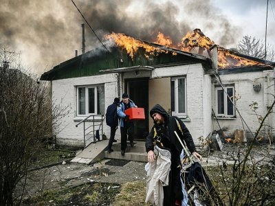 Des personnes sortent des affaires d'une maison en feu après un bombardement russe à Irpin, en Ukraine, le 4 mars 2022 - Aris Messinis [AFP]