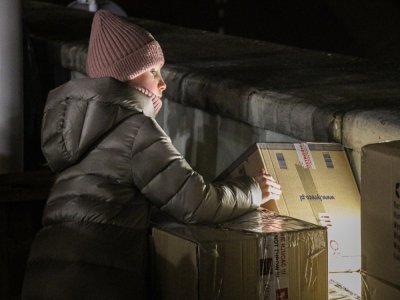 Une petite fille polonaise se glisse entre les cartons du plus grand point de collecte de Rzeszow pour prêter main-forte aux adultes en train de remplir les bus d'aides humanitaires. Une lueur d'espoir.