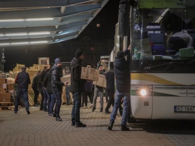 Des bénévoles polonais et ukrainiens forment une chaîne humaine pour rapidement charger les bus avec des cartons remplis de produits de première nécessité.