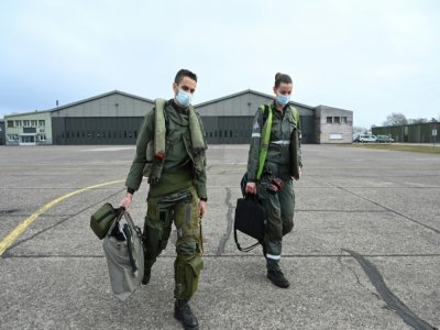 Le major Mickaël (g) se dirige avec sa mécanicienne vers son Mirage 2000-5F pour aller assurer une mission de "police du ciel" au-dessus des pays baltes, le 13 mars 2022, sur la base de Luxeuil-Saint-Sauveur, en Haute-Saône - SEBASTIEN BOZON [AFP]