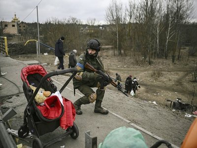 Un militaire ukrainien en position alors que des civils évacuent la ville ukrainienne d'Irpin, le 13 mars 2022 - Aris Messinis [AFP]