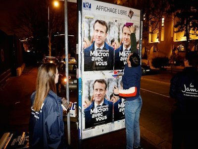 Des sympathisants de LREM collent des affiches de campagne d'Emmanuel Macron, à Vanves, en région parisienne, le 16 mars 2022 - Ludovic MARIN [AFP]