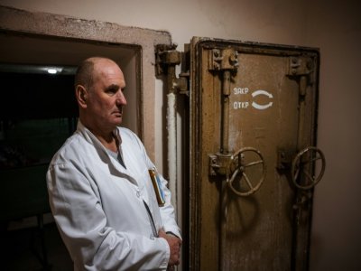 Un médecin de la pension neuropsychiatrique pour hommes de Novo-Bilytsky devant l'entrée du bunker de l'établissement, le 12 mars 2022 dans les environs de Kiev - Dimitar DILKOFF [AFP]
