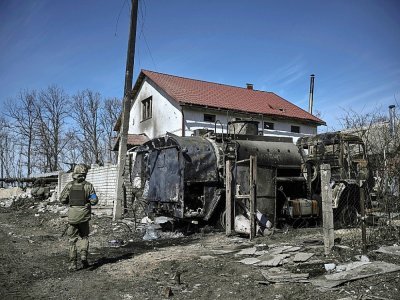 Un militaire ukrainien passe devant un véhicule russe détruit dans le village de Mala Rogan, à l'est de Kharkiv, après la reprise du village par les troupes ukrainiennes, le 28 mars 2022 - Aris Messinis [AFP]
