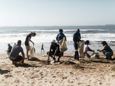 Des volontaires ramassent des détritus le 15 avril 2022 sur la plage près de Durban, après les inondations et glissements de terrain qui ont frappé l'est de l'Afrique du Sud - RAJESH JANTILAL [AFP]