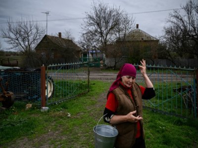 Olga Touss devant une maison endommagée par des bombardements dans le village de Mala Tokmachka, près du front, le 23 avril 2022d ans le sud de l'Ukraine - Ed JONES [AFP]