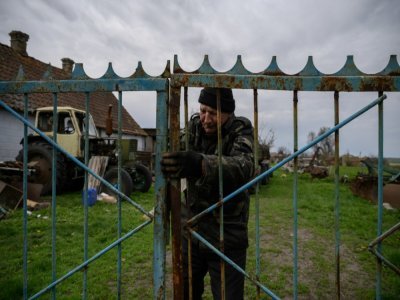 Vassili Kouchtch ferme la grille de la ferme où il travaille à Mala Tokmachka, le 23 avril 2022 en Ukraine - Ed JONES [AFP]