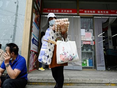 Une femme quitte un supermarché après avoir acheté de la nourriture et des produits ménagers à Pékin, le 25 avril 2022 - Jade GAO [AFP]