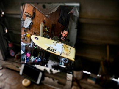 Le surfeur cubain Frank Gonzalez répare une planche dans sa maison à La Havane, le 14 avril 2022 - YAMIL LAGE [AFP]