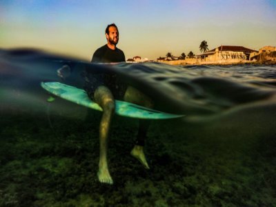 Le surfeur cubain Ayax Borrero assis sur sa planche sur la côte de La Havane, le 4 avril 2022 - YAMIL LAGE [AFP]