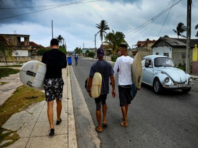 Des surfeurs avec leurs planches dans une rue de Santa Fe, à l'ouest de La Havane, le 16 avril 2022 à Cuba - YAMIL LAGE [AFP]