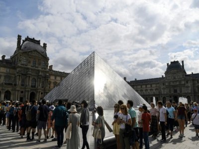 Des touristes font la queue devant l'entrée de la pyramide du Louvre à Paris le 19 juillet 2019 - ALAIN JOCARD [AFP/Archives]