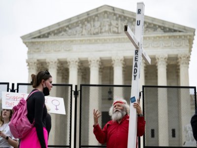 Un opposant au droit à l'avortement et une militante pro-choix face à face devant la Cour suprême des Etats-Unis, le 5 mai 2022 à Washington - Jim WATSON [AFP]