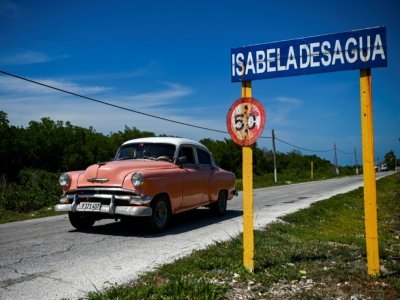 Une vieille voiture américaine face au panneau de Isabela de Sagua, à Cuba le 27 avril 2022 - YAMIL LAGE [AFP]