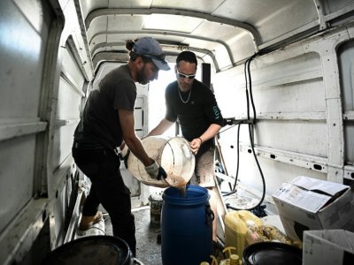 Des membres de l'association Roule ma frite transvasent des huiles de friture usagées collectées auprès de restaurateurs, à Château-d'Oléron, le 10 mai 2022 - Philippe LOPEZ [AFP]