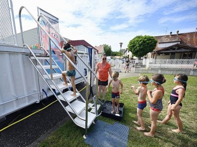 Des enfants s'apprêtent à prendre une leçon de natation dans une piscine itinérante fabriquée dans un ancien container, le 13 juillet 2022 à Hangenbieten, dans le Bas-Rhin - Frederick FLORIN [AFP]