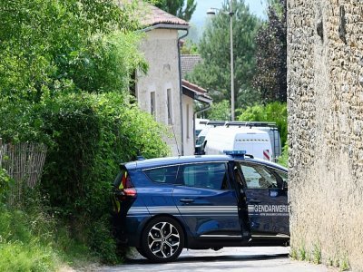 Une voiture de gendarmerie bloque une voie menant à la maison où un homme a tué cinq personnes avant d'être abattu par le GIGN, le 20 juillet 2022 à Douvres, dans l'Ain - Jean-Philippe KSIAZEK [AFP]