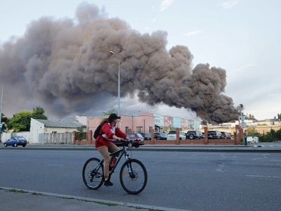 Une femme sur un vélo passe devant un entrepôt visé par une frappe russe à Odessa, le 16 juillet 2022 - Oleksandr GIMANOV [AFP]