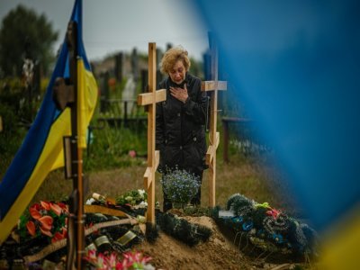 Une femme en deuil devant une tombe d'un cimetière à Kharkiv, le 21 mai 2022 - Dimitar DILKOFF [AFP]