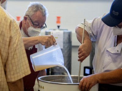 Un employé de la maison de retraite aide un résident de la maison de retraite d'Atzgersdorf en Autriche, à brasser de la bière à Vienne, le 21 juillet 2022. - Alex HALADA [AFP]