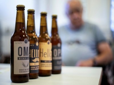 Rupert Jaksch, résident de la maison de retraite d'Atzgersdorf en Autriche, est assis derrière des bouteilles de bière, à Vienne le 21 juillet 2022 - Alex HALADA [AFP]