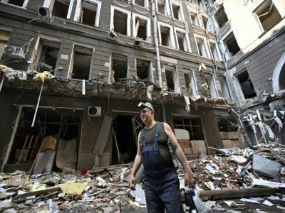 Un ouvrier dans une cour au milieu des débris après une attaque contre un centre commercial et des bureaux dans le centre de Kharkiv, le 27 juillet 2022 - Genya SAVILOV [AFP]