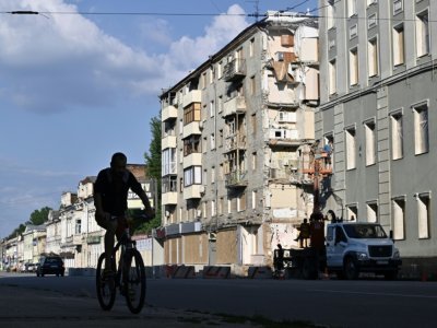 Un homme circule en vélo devant des immeubles détruits dans le centre de Kharkiv, le 27 juillet 2022 - Genya SAVILOV [AFP]
