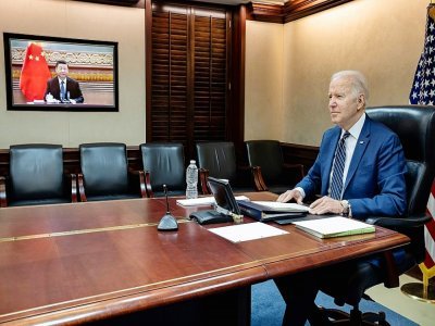 Le président américain Joe Biden (d) s'entretient avec son homologue chinois Xi Jinping (dans l'écran) par visioconférence depuis Washington, le 18 mars 2022 - - [The White House/AFP/Archives]