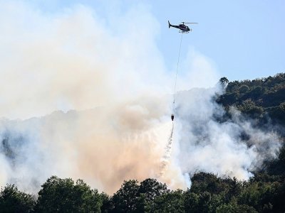 Un hélicoptère largue de l'eau sur des arbres en feu près de Cernon, dans le Jura, le 11 août 2022 - Jean-Philippe KSIAZEK [AFP]