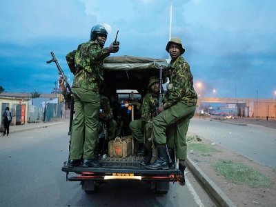 Un véhicule de la police kenyane passe devant des débris enflammés sur la route après une manifestation des partisans de Raila Odinga, candidat malheureux à la présidentielle, à Kisumu, dans l'ouest du Kenya, le 15 août 2022 - YASUYOSHI CHIBA [AFP]