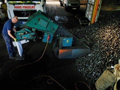 Un employé remplit des sacs de charbon dans un hangar de stockage de l'entreprise Hans Engelke Energie, le 10 août 2022 à Berlin - Carsten Koall [AFP]