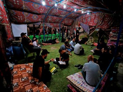 Des manifestants, partisans d'une coalition rivale du Courant sadriste, sont dans une tente installée sur un pont menant à la Zone verte à Bagdad, le 15 août 2022 - AHMAD AL-RUBAYE [AFP]