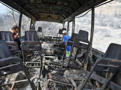 Un bus calciné où une douzaine de personnes ont péri après avoir été piégées par les flammes, le 18 août 2022 à El Kala, en Algérie - - [AFP]